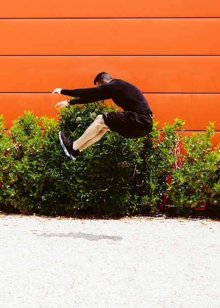 Foto gratuita joven atleta masculino haciendo un salto de longitud en la arena