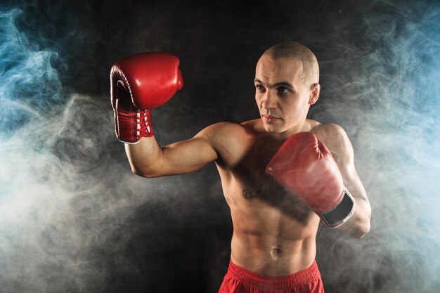 El joven atleta masculino kickboxing sobre un fondo de humo azul