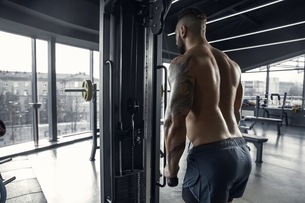 Joven atleta musculoso practicando en el gimnasio con las pesas