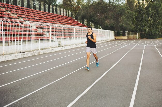 Joven atlético corriendo en el estadio en la mañana