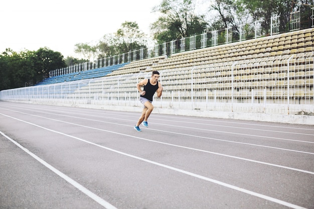 Joven atlético corriendo en el estadio en la mañana