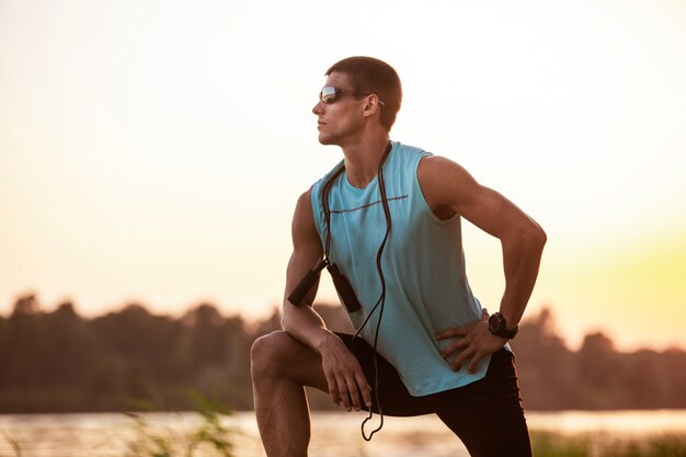 Joven atlético ejercitándose, entrenando en la orilla del río al aire libre.