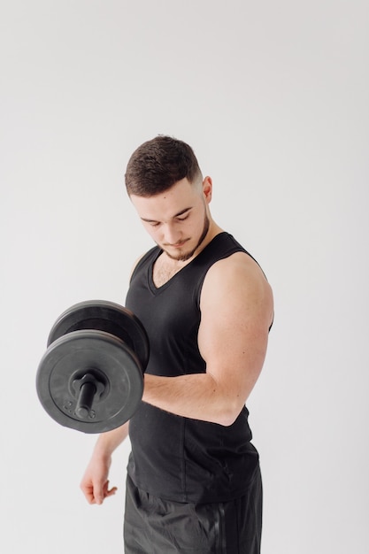 Joven atlético haciendo entrenamientos en casa, hombre haciendo entrenamiento, calentamiento antes del ejercicio con pesas.