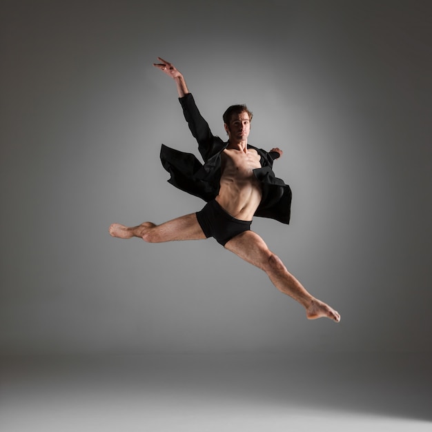 joven y atractiva bailarina de ballet moderno saltando sobre blanco