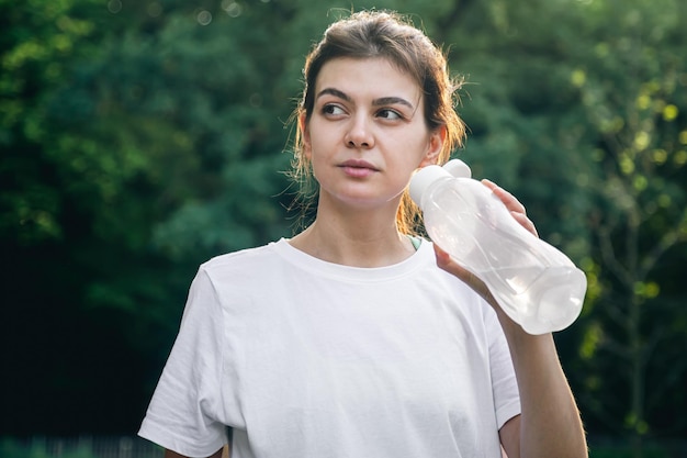 Foto gratuita una joven atractiva bebe agua después de hacer ejercicio al aire libre.