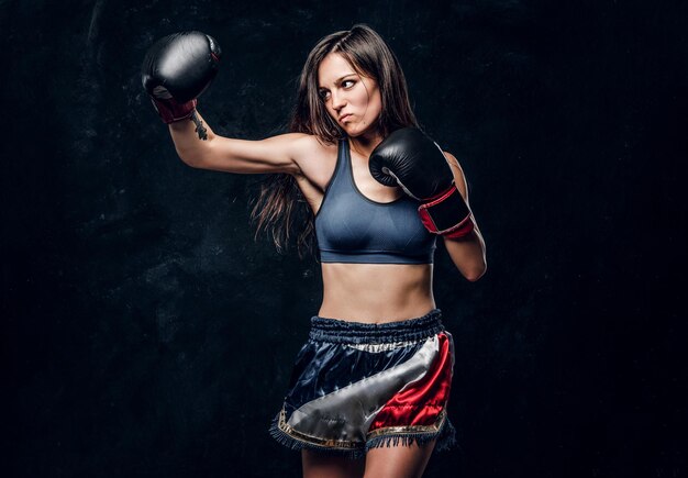 Una joven y atractiva boxeadora con cabello largo y guantes de boxeo está lista para pelear.