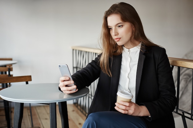 joven atractiva en café con smartphone