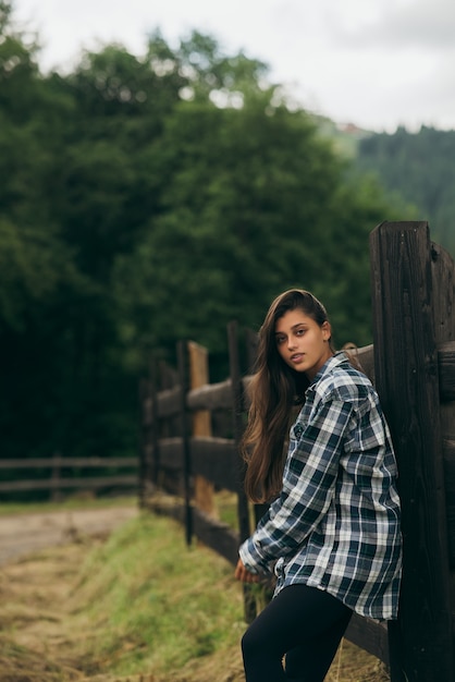 Una joven y atractiva mujer caucásica de pie junto a una valla