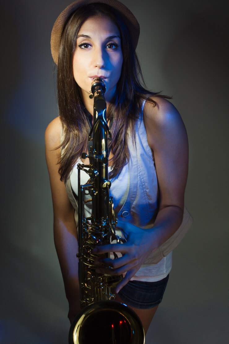 Foto gratuito joven y atractiva mujer con sombrero tocando el saxofón