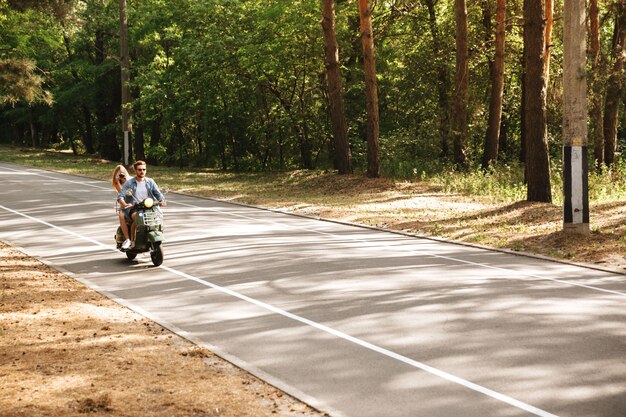 Joven atractiva pareja amorosa en scooter al aire libre. Mirando a un lado