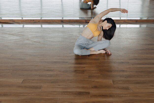 Joven atractiva en un piso de madera haciendo yoga, estiramientos y relajación