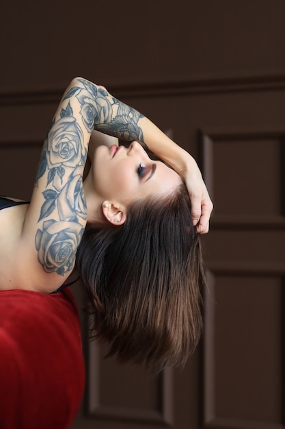 Foto gratuita joven atractiva con tatuaje posando