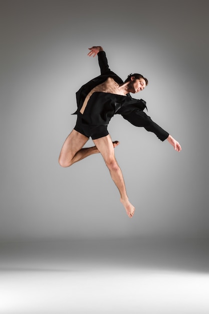 El joven y atractivo bailarín de ballet moderno saltando sobre fondo blanco.