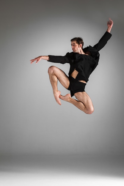 El joven y atractivo bailarín de ballet moderno saltando sobre fondo blanco.