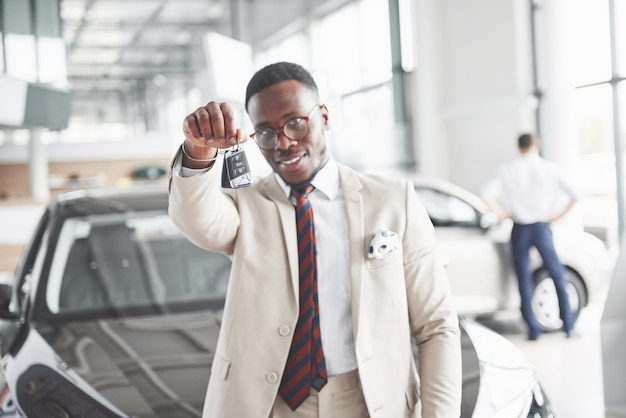 El joven y atractivo empresario negro compra un coche nuevo, los sueños se hacen realidad.