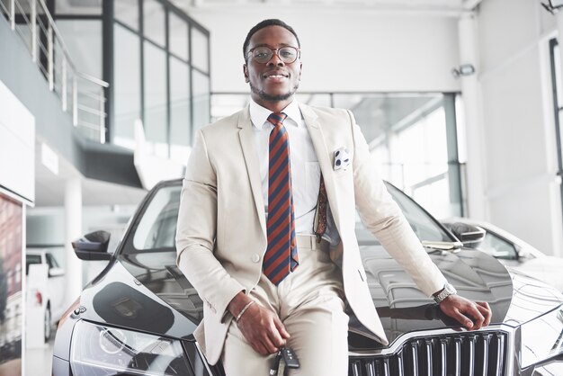 El joven y atractivo empresario negro compra un coche nuevo, los sueños se hacen realidad.