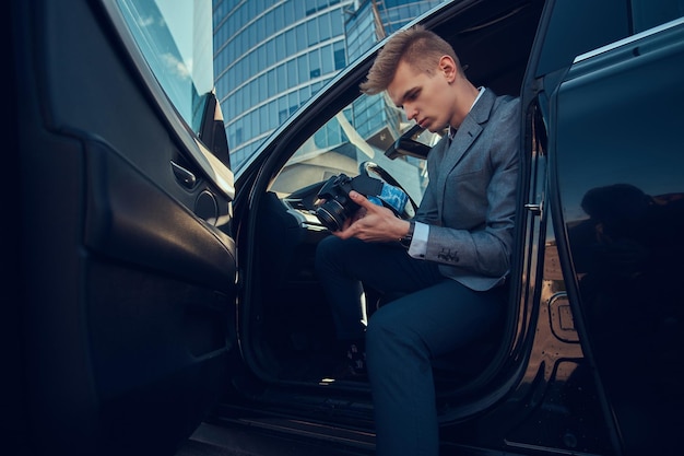 Un joven y atractivo hombre de negocios está mirando su teléfono móvil mientras está sentado en el auto.