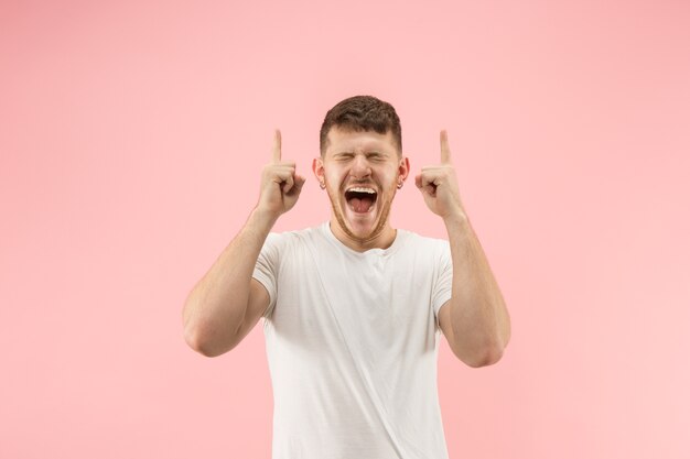 El joven atractivo mirando sorprendido aislado en rosa