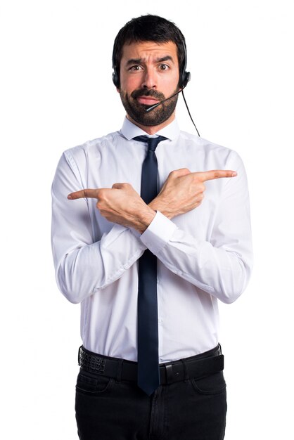 Joven con un auricular apuntando a los laterales tener dudas