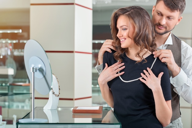 Foto gratuita joven ayudando a su novia con collar apropiado en el je