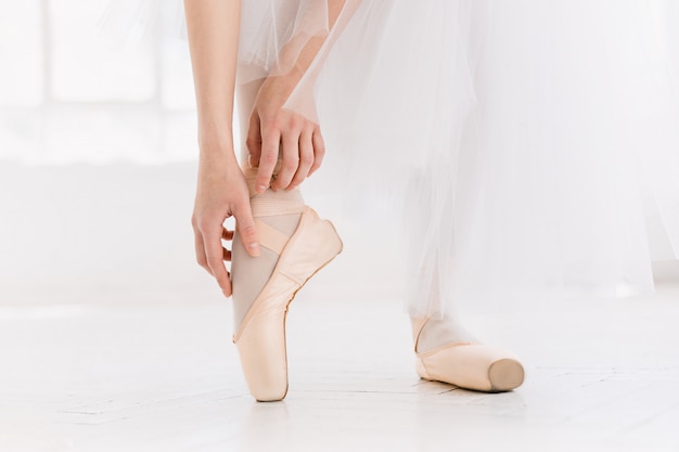 Foto gratuita joven bailarina bailando, primer plano en las piernas y los zapatos, de pie en posición de punta.
