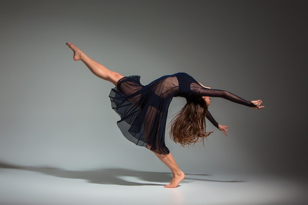 Joven bailarina hermosa vestida de negro posando sobre un fondo de estudio gris oscuro. Moderno, Contemporáneo, improvisación