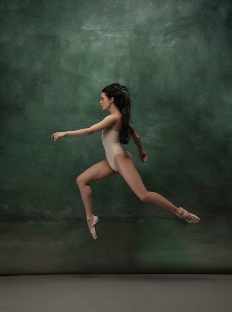 Joven bailarina tierna elegante en espacio de estudio verde oscuro