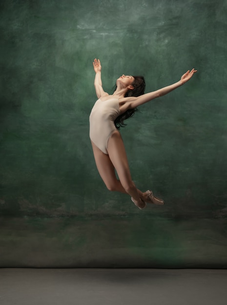 Joven bailarina tierna elegante en espacio de estudio verde oscuro