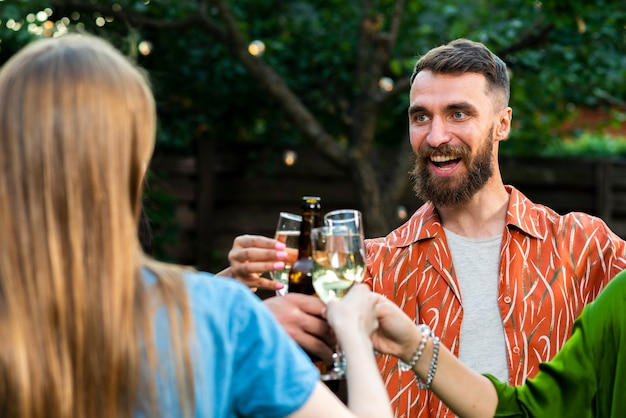 Joven barbudo brindando bebidas con amigos