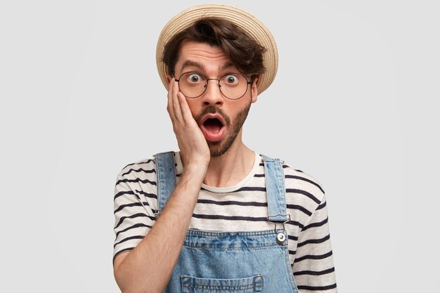 Joven barbudo con gafas redondas y overoles de mezclilla