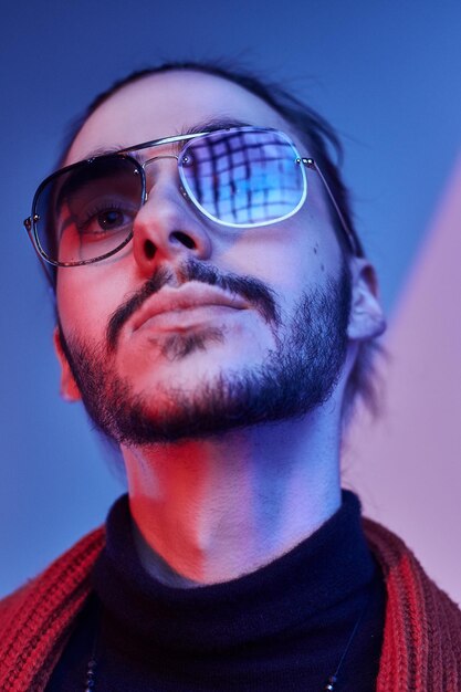 Un joven barbudo posa para el fotógrafo bajo una luz inusual, con gafas de sol.