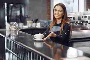 Foto gratuita joven barista hace café y sonríe