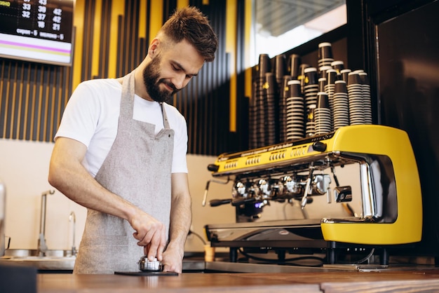 Joven barista masculino preparando café en una cafetería
