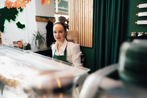 Joven barista de pie dentro del mostrador de café