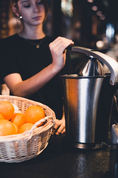 Joven barman juicing naranjas en el restaurante