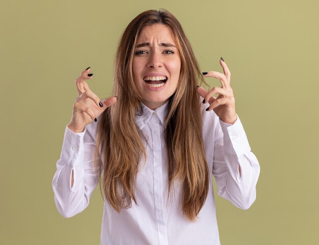 Joven bastante caucásica molesta tiene las manos cerca de la cara en verde oliva