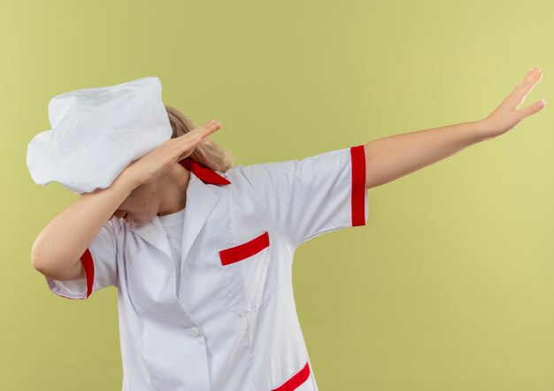 Joven bastante cocinero en uniforme de chef haciendo gesto de dab aislado sobre fondo verde