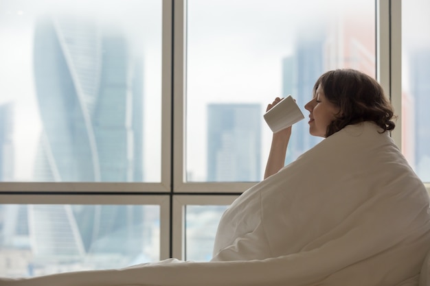 Joven beber café en la cama