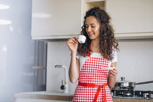 Joven bebiendo café en la cocina por la mañana