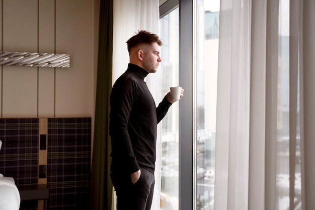 Joven bebiendo café en una habitación de hotel