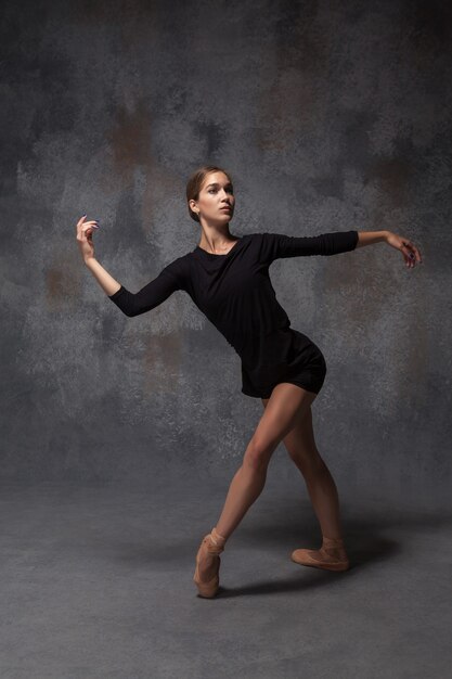 La joven y bella bailarina de estilo moderno posando sobre un fondo gris de estudio