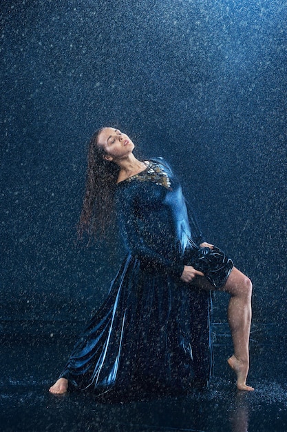 joven y bella bailarina moderna bailando bajo gotas de agua