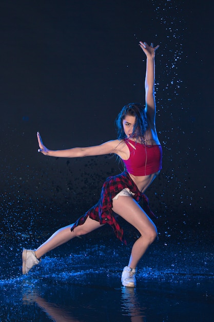 La joven y bella bailarina moderna bailando bajo gotas de agua