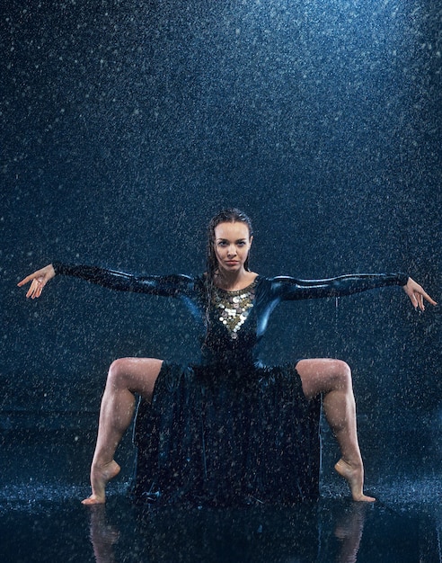 La joven y bella bailarina moderna bailando bajo gotas de agua