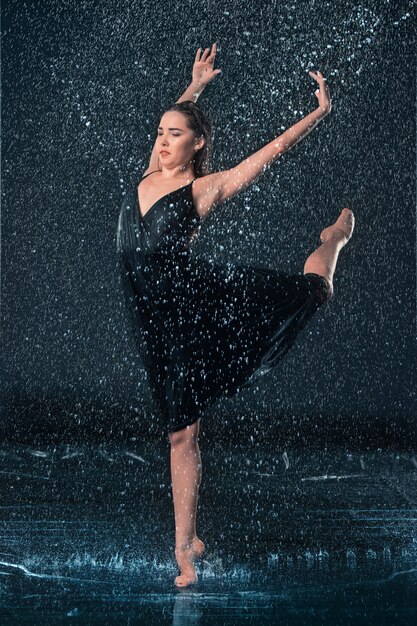 La joven y bella bailarina moderna bailando bajo gotas de agua