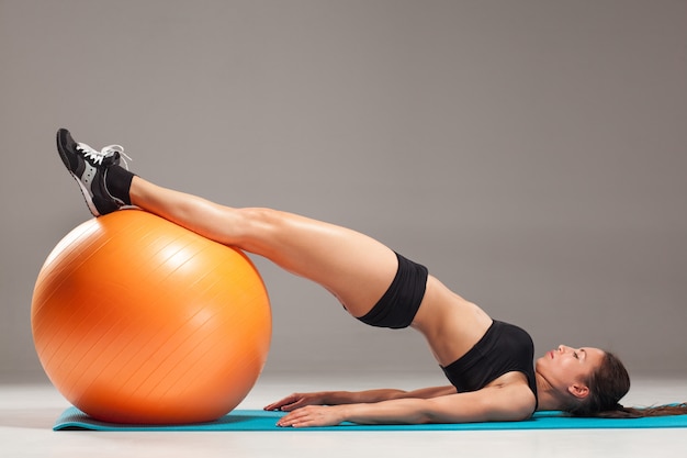 La joven, bella, deportista haciendo ejercicios en una fitball