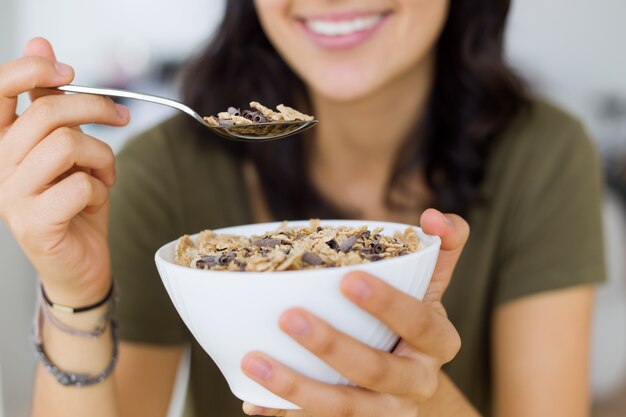 Joven y bella mujer disfrutando de desayuno en casa.