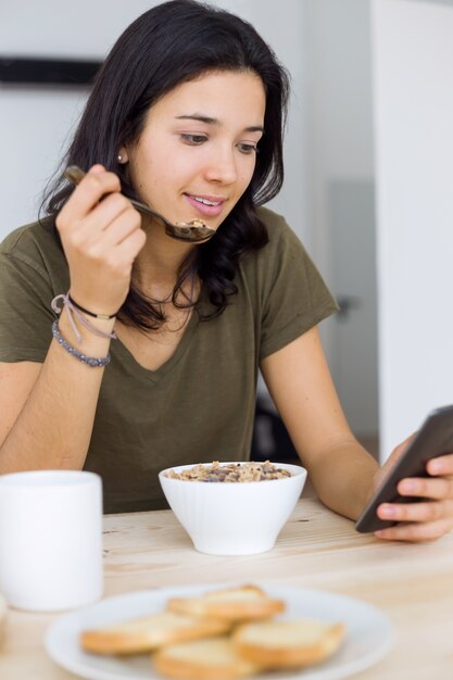 Joven y bella mujer disfrutando de desayuno en casa.