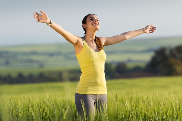 Joven y bella mujer disfrutando de la primavera de pie en un campo de cereales