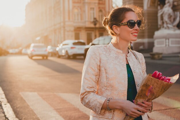 Joven y bella mujer elegante caminando por las calles de la ciudad en la puesta del sol